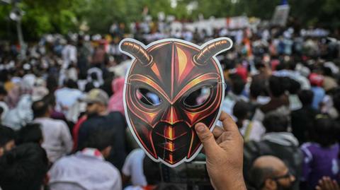 A Cockroach Janta Party (CJP) supporter holds a cockroach mask during a protest over alleged irregularities in the country's major examinations, in New Delhi on June 6, 2026