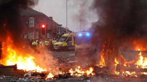 Police pictured near a burning police vehicle after disorder broke out on July 30, 2024 in Southport, England.