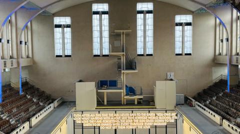 Artwork inside art deco swimming pool, words are lit up.