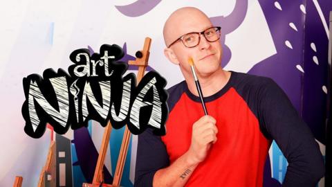 Art Ninja, a bald man holds up a paint brush, he is infront of a canvas.