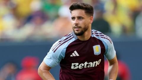 Alex Moreno, wearing Aston Villa's claret and blue kit, looks across to his right as he runs