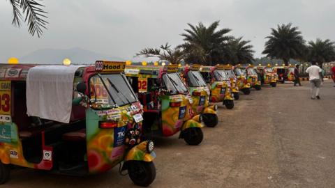 Rows of tuk-tuks parked. They are yellow and a lot of other vibrant colours 