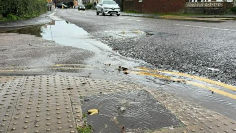 Dirty water bubbling out of a manhole cover in the pavement