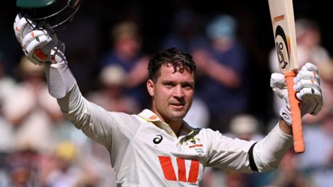 Australia wicketkeeper Alex Carey raises his bat after hitting a century