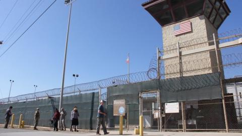 People walk past a guard tower outside the fencing of Camp 5 at the US Military"s Prison in Guantanamo Bay, Cuba on January 26, 2017.