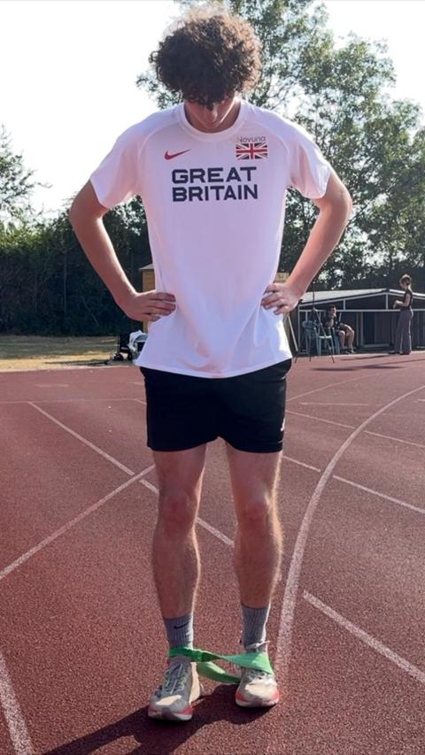 Man in a white Great Britain shirt looking down at his feet. 
