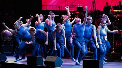 A group of teenagers performing a dance on a stage