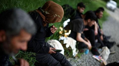 Migrants sit in the forest, after crossing the Belarusian-Polish border, June 2024