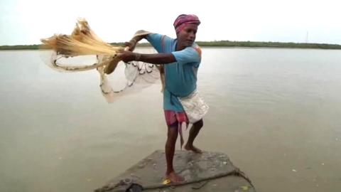 Man casts net out into water