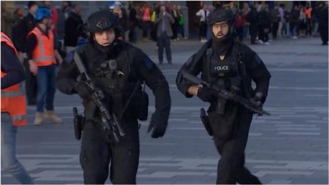 Armed policemen running in central Auckland