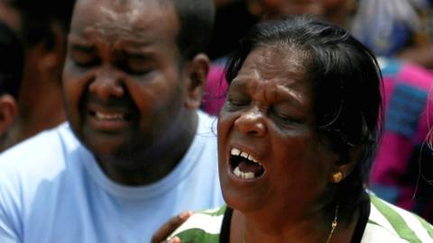 Family members of victims react during a rescue mission after a garbage dump collapsed and buried dozens of houses in Colombo