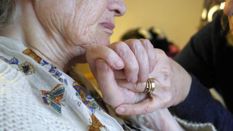 Carer holding woman's hand