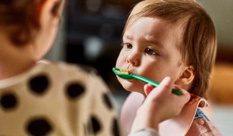 Baby being fed rice from a spoon