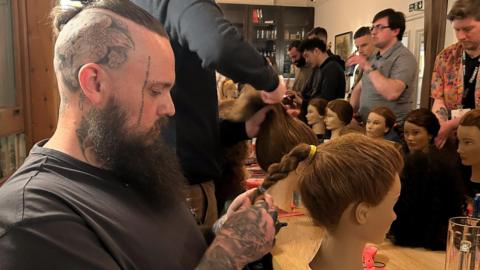 Tattooed father of two Paul Jessop gets to grips with a plait on his mannequins head. 