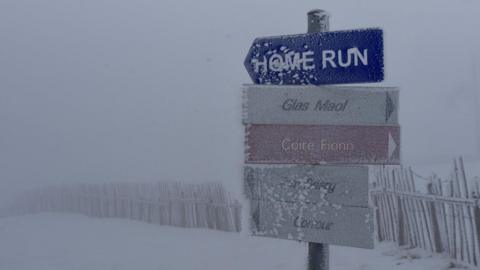 The signs read: "Home run" "Glas Maol" "Coire Fionn" and "Corrour". The signs are covered in snow and rime ice.