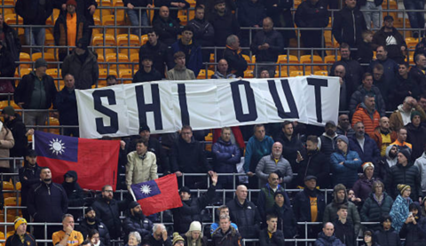 Wolves fans hold a banner that reads 'SHI OUT' and Taiwan flags