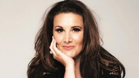 Sam Bailey looking at the camera with her hand on her chin.