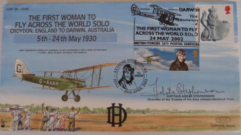 An envelope has a drawing of Amy Johnson's green Gipsy Moth plane, with people standing on the ground waving to her as she comes into land on fields with a blue sky.