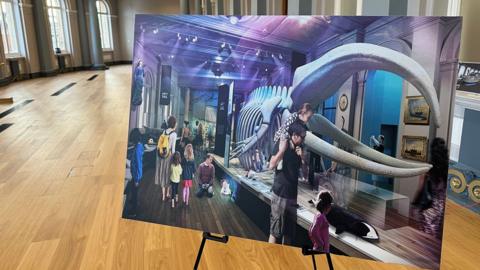 A view of a hall in the refurbished museum with a large photograph in the foreground showing how it will look when the whale skeleton and other exhibits are restored