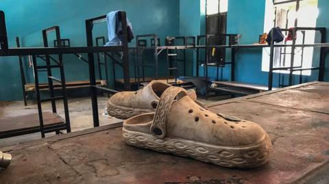 Shoes lie abandoned on a bunk bed in a school dormitory. 