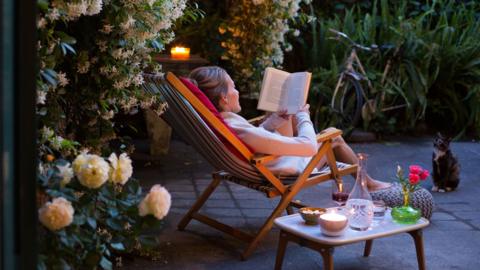 Woman sitting in a deckchair in the garden reading a book