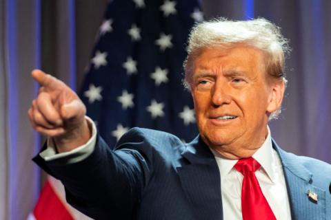 US President-elect Donald Trump wears a suit with a red tie and points with his right hand