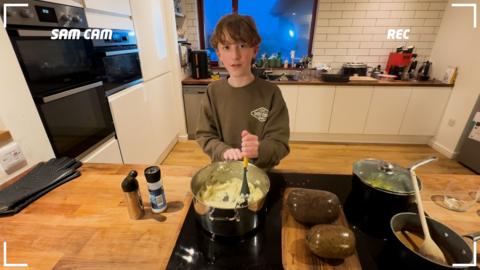A boy in a kitchen mashing mash potato.