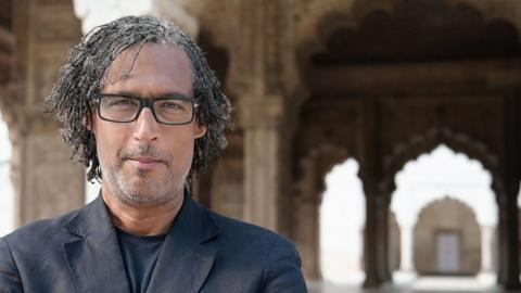 David Olusoga stands in front of a monument in India.