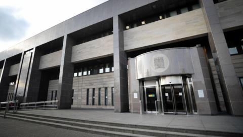 Glasgow Sheriff Court is a grey building with a rotating entrance and a brutalist exterior