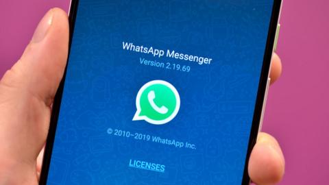 WhatsApp logo on a phone being held in a hand