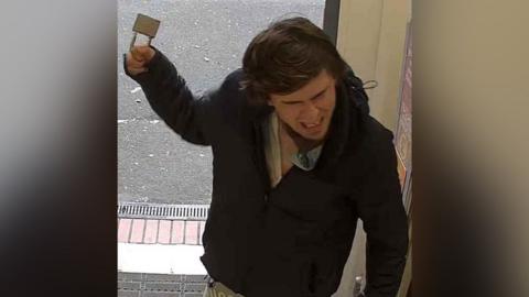 An image of Sam Sharpe brandishing a padlock during an incident at a Sainsbury's store in Lenton