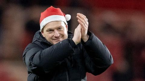 Kim Hellberg applauding wearing a Santa hat