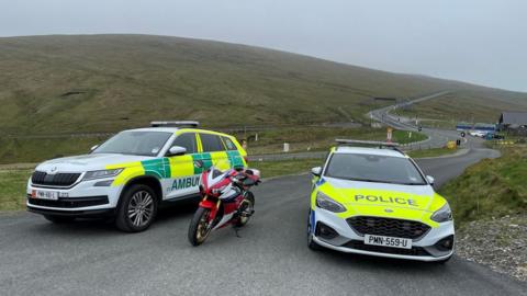 Ambulance, motorbike and police car parked on the Mountain Road by the Bungalow