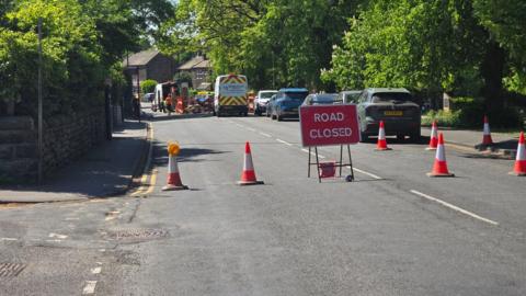 A red 'road closed' sign with cones blocking the road.