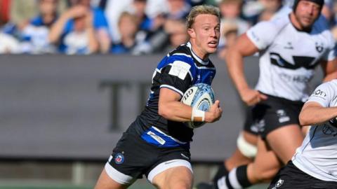 Sam Harris runs with the ball tucked under his right arm during a match as Bristol Bears players run alongside him