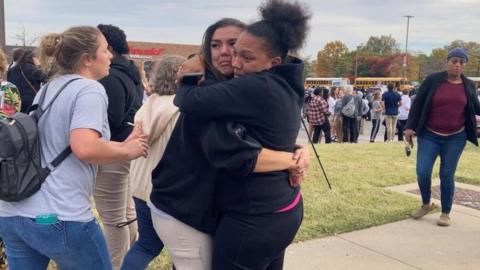 People embrace outside the school