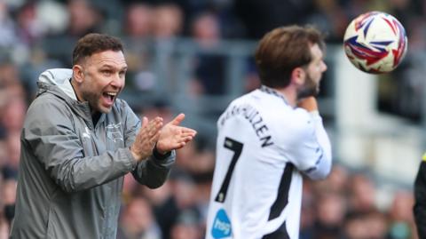 John Eustace claps his hands while watching his Derby side