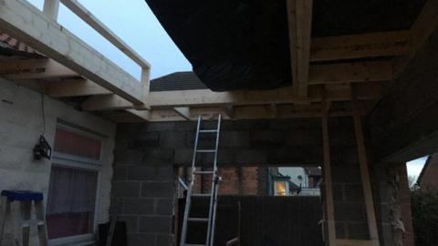 A photo of the scene of the accident, with a ladder propped up leading to roof beams
