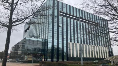 A large modern building covered in mirrored windows. 