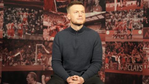 Kim Hellberg pictured sitting down surrounded by images of memorable moments in Middlesbrough's history