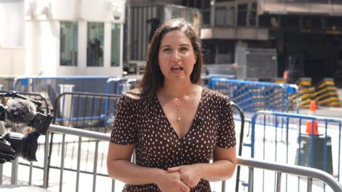 Nada Tawfik stands on a sidewalk outside Madison Square Garden, wearing a brown dress with white dots.