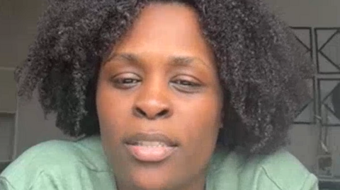 Jacinta Batalha has a light green top and black permed hair.