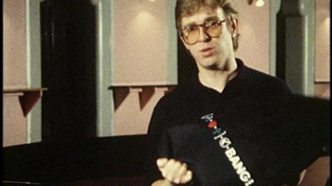 Presenter holding a band T-shirt.