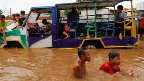 Children play at an area flooded after heavy rains in Jakarta