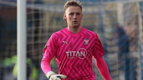 George Sykes-Kenworhy wearing a pink York City goalkeeper's kit