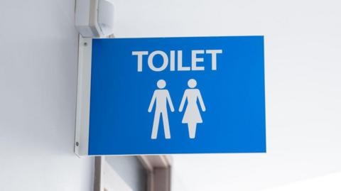 A blue male and female toilet sign mounted on a white wall.