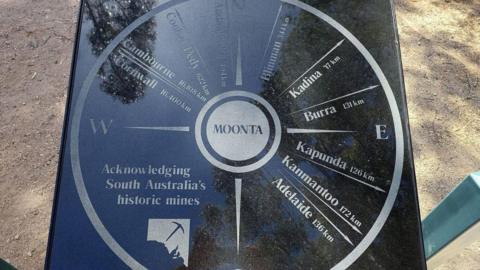 A close up of the sundail. It is black with gold writing. The word Camborne is spelt Cambourne.