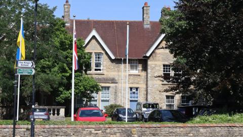 A building with a carpark and flags flying in front of it.