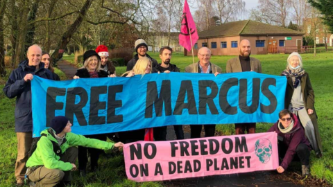 Protesters pose with a banner calling for Marcus Decker to be freed from prison