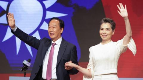 Foxconn founder Terry Gou (L) and running mate Lai Pei-hsia (R) wave during a press conference